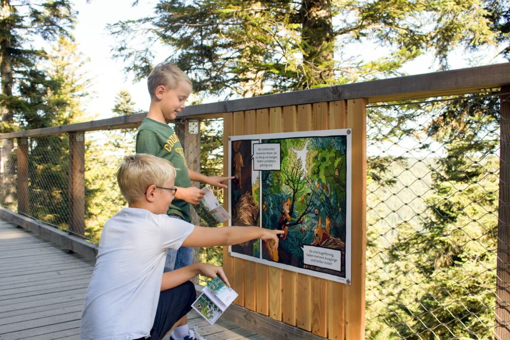 zwei Jungs schauen sich eine Comic-Infotafel an