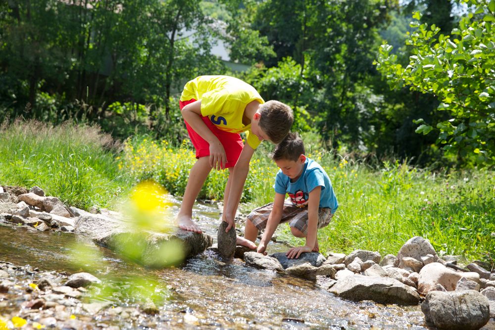 Kinder spielen am Bach.