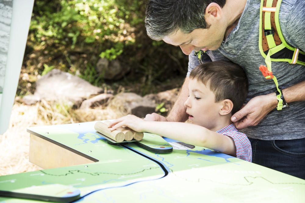 Ein Mann und ein Junge stehen vor einer interaktiven Station.