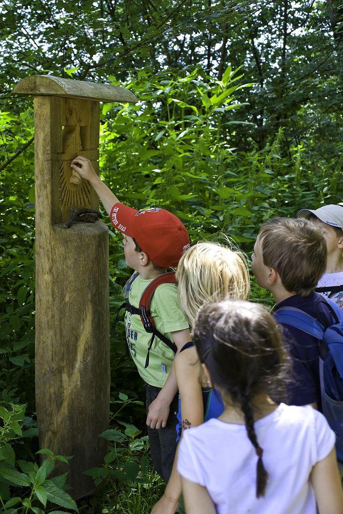 Kinder schauen eine Holzfigur an