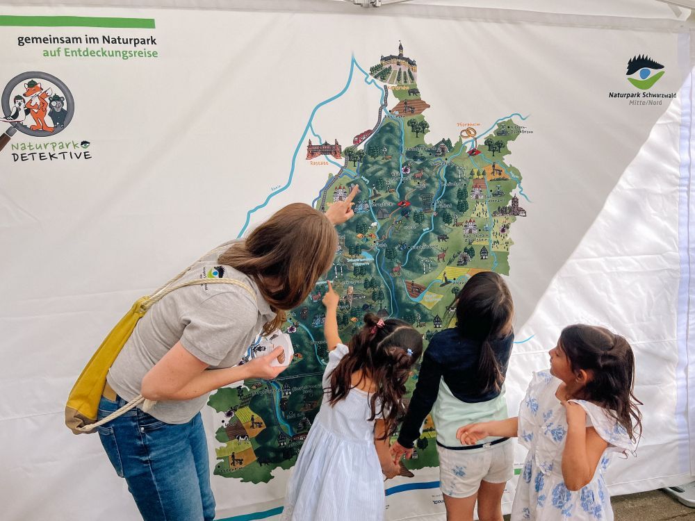 Eine Frau und Kinder schauen sich die Naturpark-Karte an.