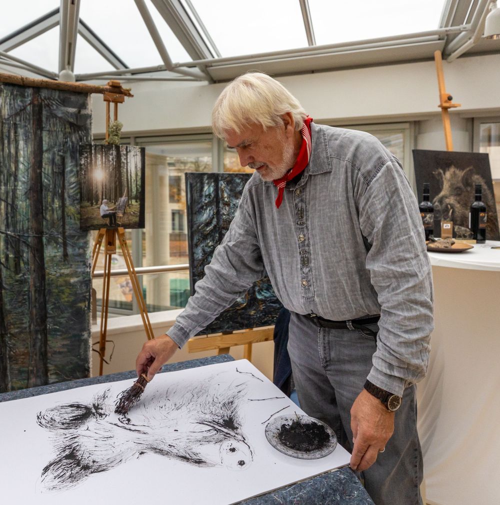 Ein Mann malt ein Wildschwein mit einem kleinen Holzbesen.
