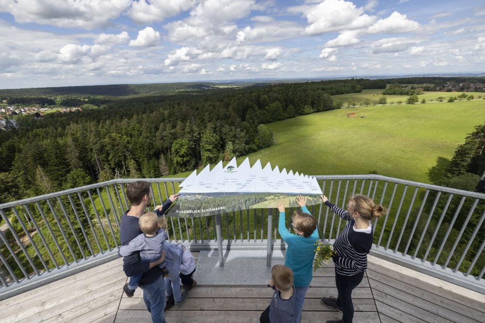 Eine Familie mit kleinen Kindern an der Naturpark-AugenBlick-Tafel auf dem Turm in Schömberg.