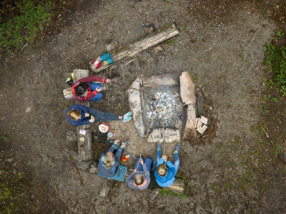 Fünf Menschen sitzen um eine Feuerstelle herum.