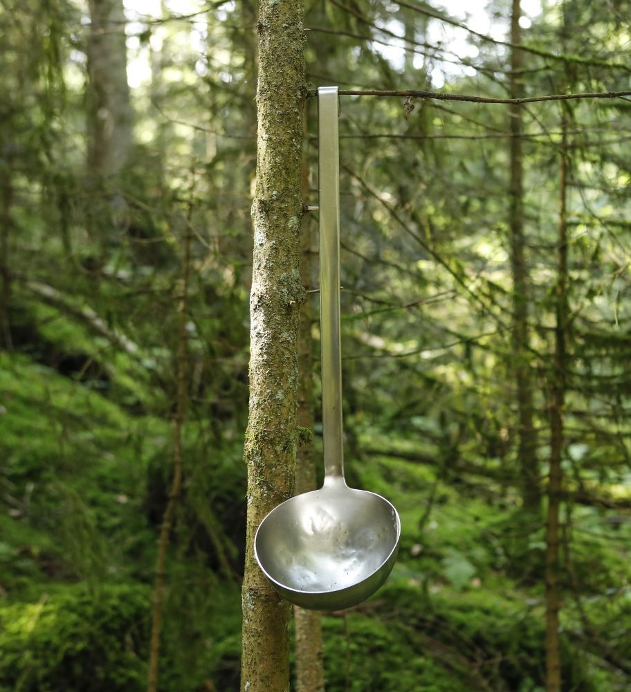 Schöpfkelle hängt an einem Ast am Baum.