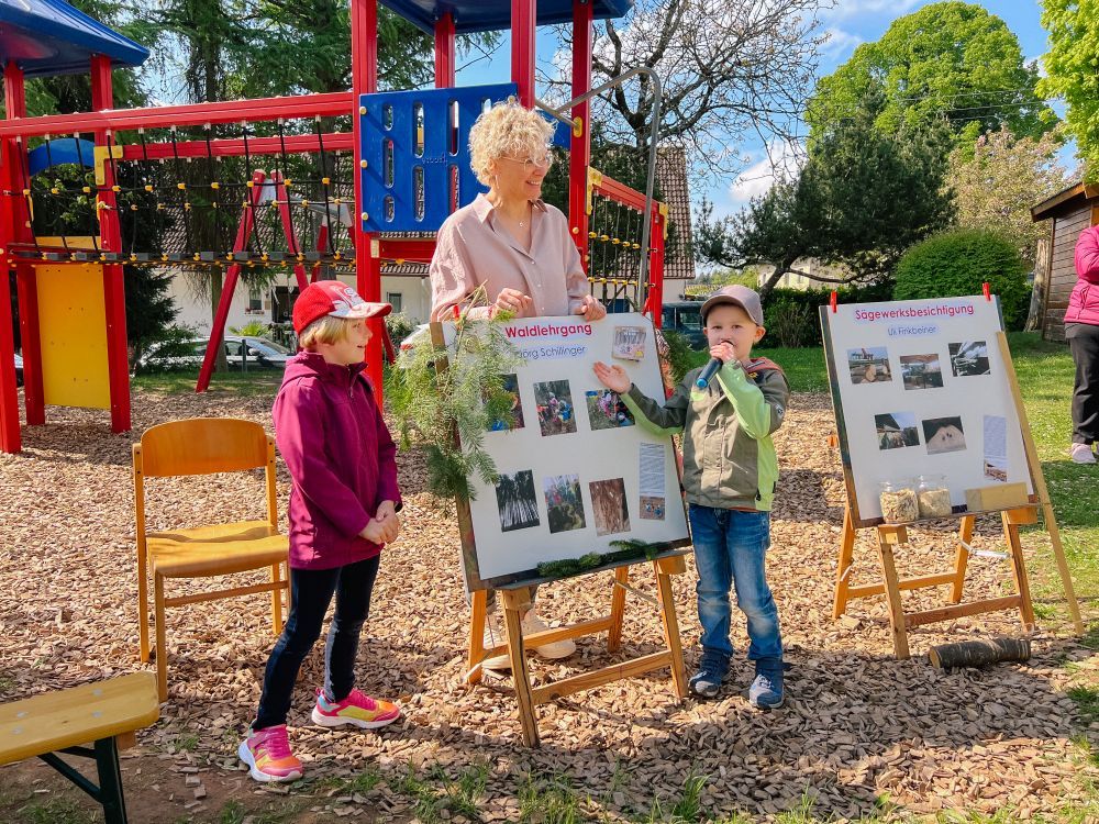 Zwei Kinder und eine Frau stellen anhand von Plakaten die Naturpark-Projekte vor.