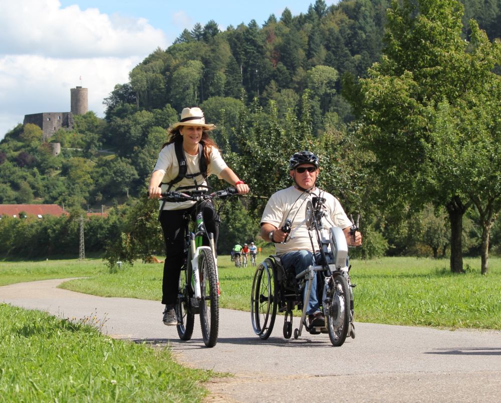 Eine Frau fährt auf einem Fahrrad, neben ihr fährt ein Mann in einem Sitzend-Bike