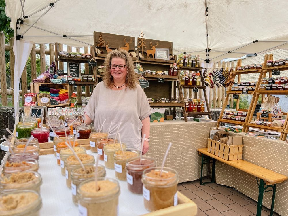 Eine Markt-Beschickern präsentiert an ihrem Stand Senf und Fruchtaufstriche sowie Gehäkeltes.