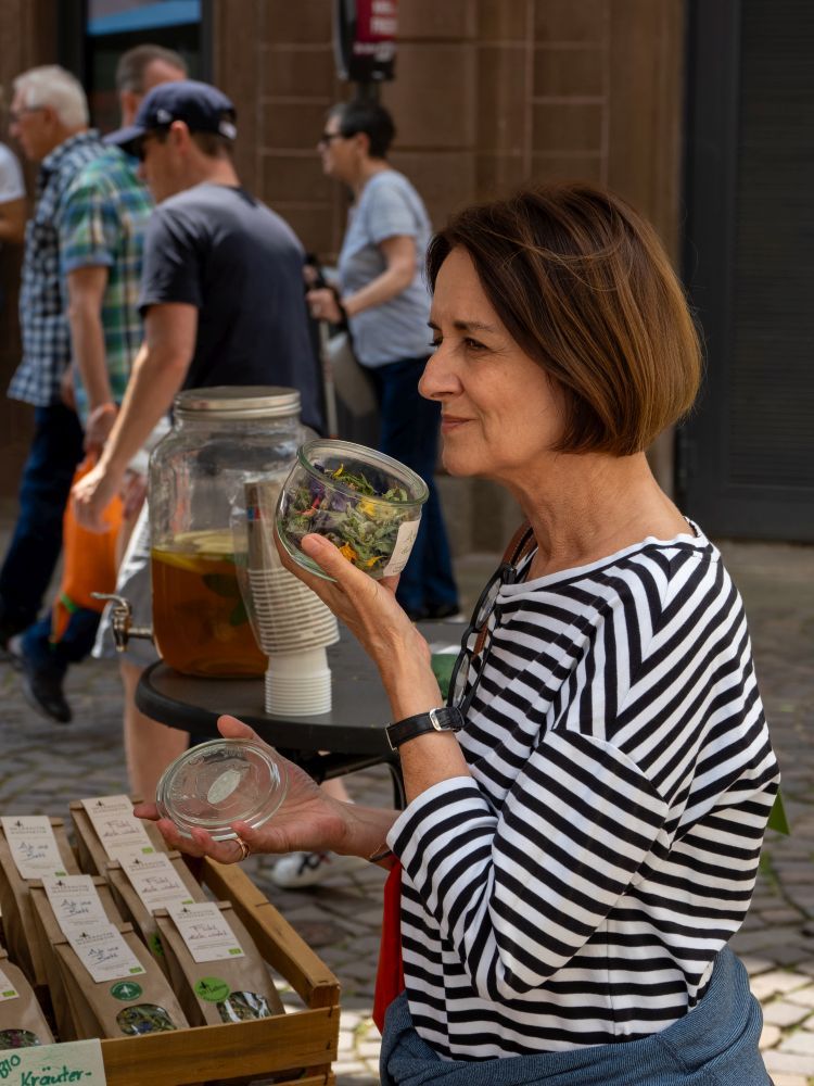 Eine Frau riecht an einer getrockneten Blütenmischung.