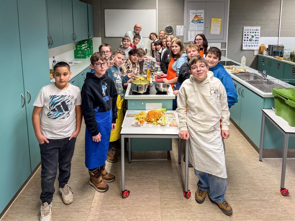 Schülerinnen und Schüler stehen für ein Gruppenbild zusammen in der Küche.