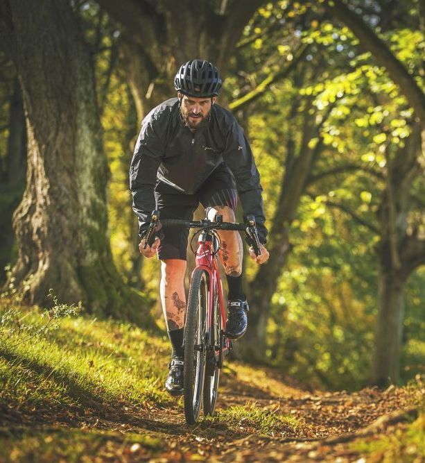 Ein Mann fährt auf seinem Gravel Bike einen Waldweg entlang.