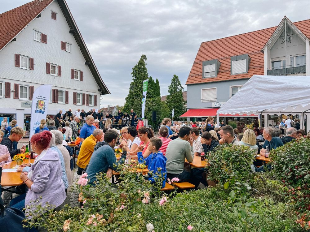 Menschen sitzen an Biertischen und essen