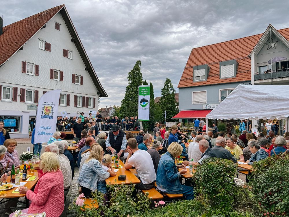 Menschen sitzen vor einer Bühne beim Essen.